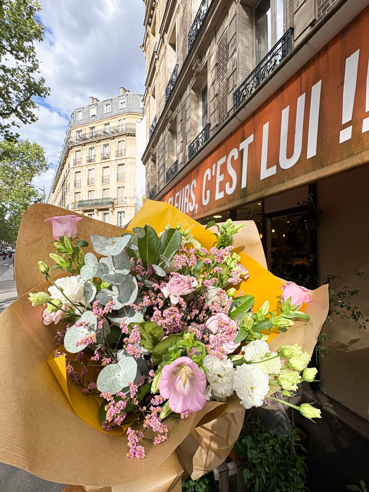 Bouquet sur mesure dans son papier kraft, devant le store de la boutique